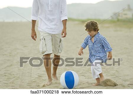 Stock Photo - Father and son playing with ball at the beach. Fotosearch