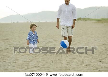 Stock Photo - Father and son playing with ball at the beach. Fotosearch