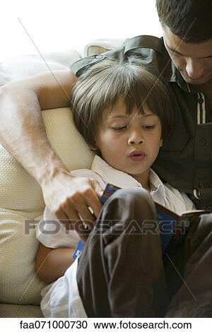Stock Image - Father and young son reading together, cropped. Fotosearch