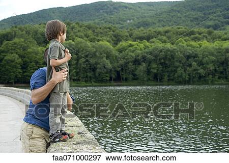 Father holding son standing on stone wall View Large Photo Image Stock Photo - Father holding son standing on stone wall. Fotosearch