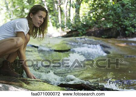 Female hiker crouching beside stream View Large Photo Image Stock Image - Female hiker crouching beside stream. Fotosearch