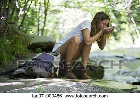 Female hiker drinking water from stream View Large Photo Image Stock Photograph - Female hiker drinking water from stream. Fotosearch