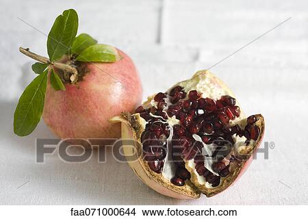 Picture - Fresh pomegranates, one cut open revealing seeds. Fotosearch