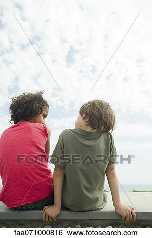 Girl and boy sitting side by side, rear view View Large Photo Image Stock Photograph - Girl and boy sitting side by side, rear view. Fotosearch