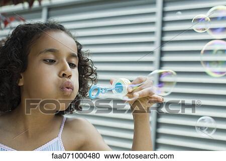 Stock Image - Girl blowing bubbles. Fotosearch