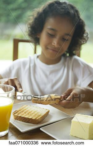 Girl buttering toast View Large Photo Image Stock Photograph - Girl buttering toast. Fotosearch