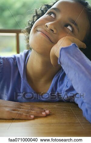Stock Image - Girl daydreaming at table. Fotosearch