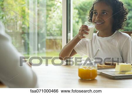 Stock Photograph - Girl drinking glass of milk at breakfast. Fotosearch