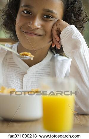 Stock Image - Girl eating breakfast, portrait. Fotosearch