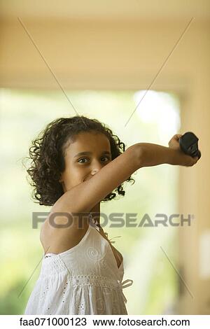Stock Image - Girl playing video game using wireless controller. Fotosearch