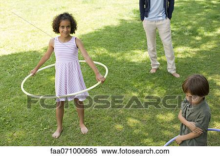 Girl playing with plastic hoop outdoors, smiling at camera View Large Photo Image Stock Photography - Girl playing with plastic hoop outdoors, smiling at camera. Fotosearch