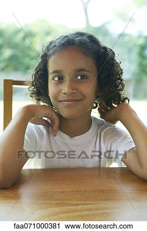 Stock Image - Girl sitting at table, portrait. Fotosearch