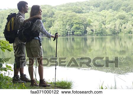 Hiking couple looking at lake View Large Photo Image Stock Image - Hiking couple looking at lake. Fotosearch