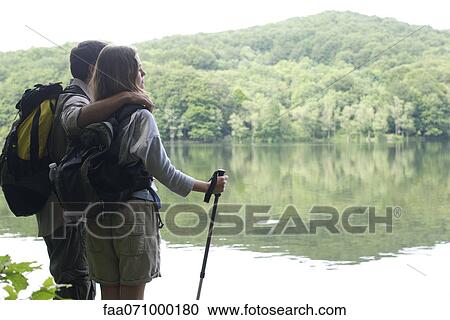 Hiking couple standing by lake View Large Photo Image Stock Image - Hiking couple standing by lake. Fotosearch