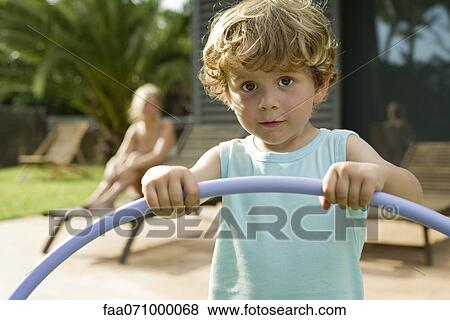 Stock Photo - Little boy holding plastic hoop, portrait. Fotosearch