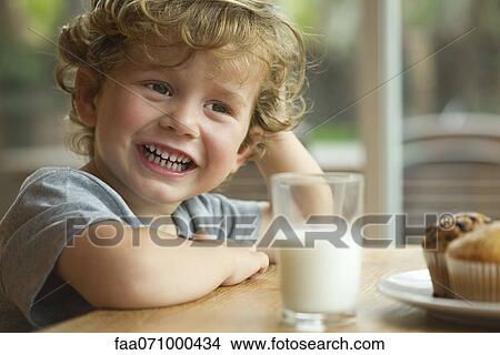Picture - Little boy sitting at table with snack, portrait. Fotosearch