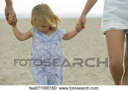 Little girl walking hand in hand with parents at the beach, cropped View Large Photo Image Stock Image - Little girl walking hand in hand with parents at the beach, cropped. Fotosearch
