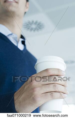 Stock Photo - Man holding disposable coffee cup, cropped. Fotosearch