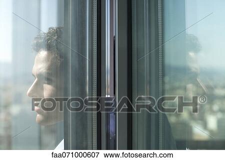 Stock Photo - Man looking out of open window. Fotosearch