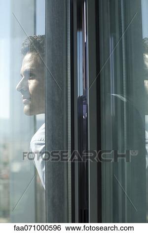 Stock Photograph - Man looking out of open window. Fotosearch