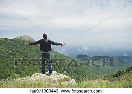 Man standing on top of rock with arms outstretched, rear view View Large Photo Image Stock Image - Man standing on top of rock with arms outstretched, rear view. Fotosearch