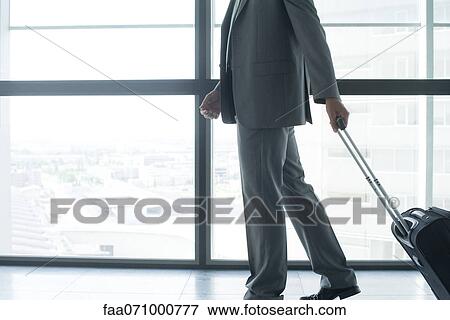 Man with wheeled suitcase, low section View Large Photo Image Stock Photo - Man with wheeled suitcase, low section. Fotosearch