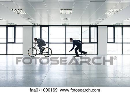 One businessman riding bicycle, the other skateboarding View Large Photo Image Stock Photo - One businessman riding bicycle, the other skateboarding. Fotosearch
