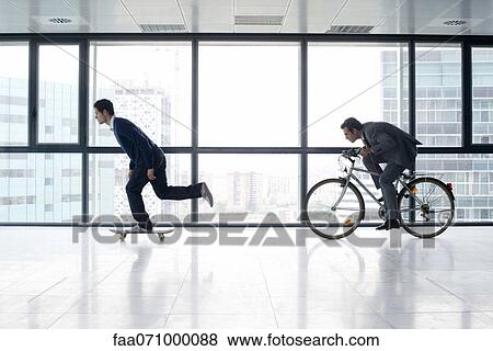 One businessman skateboarding, the other riding bicycle View Large Photo Image Stock Photo - One businessman skateboarding, the other riding bicycle. Fotosearch
