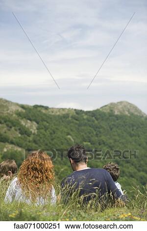 Parents and children sitting on meadow looking at mountain view, rear view View Large Photo Image Stock Image - Parents and children sitting on meadow looking at mountain view, rear view. Fotosearch