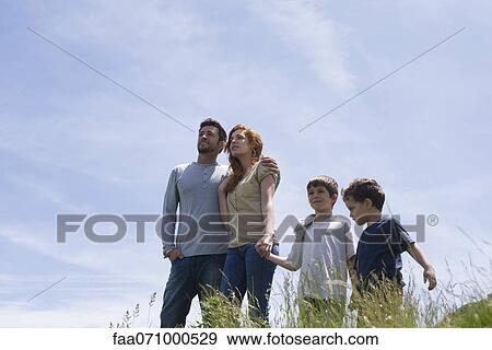 Parents and two boys standing on meadow holding hands, low angle view View Large Photo Image Stock Photo - Parents and two boys standing on meadow holding hands, low angle view. Fotosearch