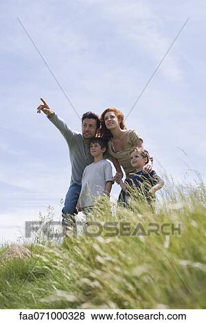 Parents and two boys standing on meadow, father pointing into distance View Large Photo Image Stock Photo - Parents and two boys standing on meadow, father pointing into distance. Fotosearch