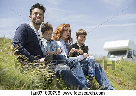 Stock Photography - Parents and young boys sitting on meadow. Fotosearch