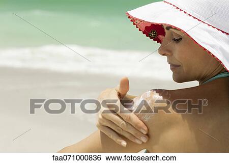 Woman at the beach applying sunscreen View Large Photo Image Stock Photograph - Woman at the beach applying sunscreen. Fotosearch