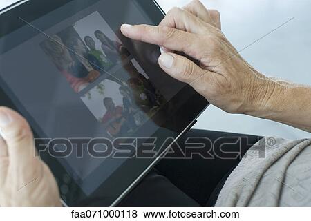 Stock Photo - Woman looking at photographs on digital tablet, cropped. Fotosearch