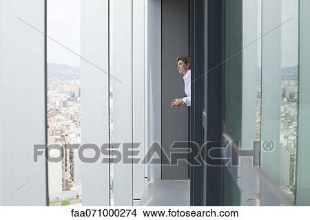 Woman looking out of office window at view of city View Large Photo Image Picture - Woman looking out of office window at view of city. Fotosearch