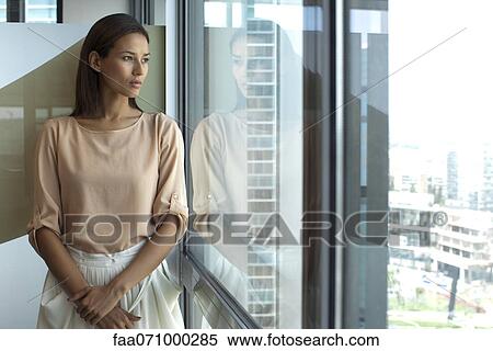 Stock Photography - Woman looking out of office window. Fotosearch