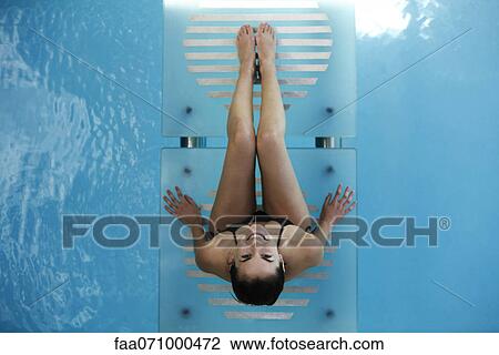 Woman relaxing on swimming pool footbridge, smiling up at camera View Large Photo Image Stock Image - Woman relaxing on swimming pool footbridge, smiling up at camera. Fotosearch