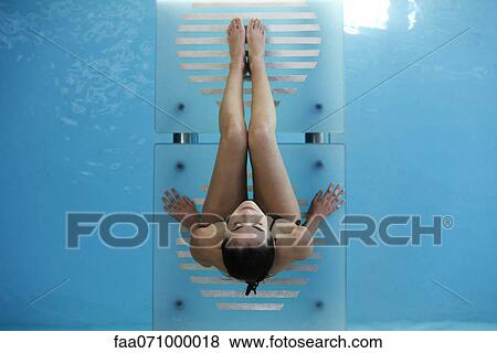 Woman relaxing on swimming pool footbridge smiling up at camera View Large Photo Image Stock Photo - Woman relaxing on swimming pool footbridge smiling up at camera. Fotosearch
