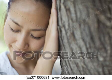 Woman resting head against tree trunk with eyes closed View Large Photo Image Stock Image - Woman resting head against tree trunk with eyes closed. Fotosearch