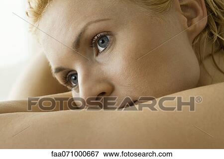 Stock Photo - Woman resting head on arm, looking away in thought. Fotosearch