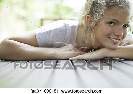 Stock Image - Woman resting head on arms, smiling, portrait. Fotosearch