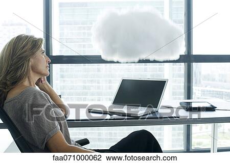 Woman sitting at desk with laptop computer. cloud above laptop computer View Large Photo Image Stock Image - Woman sitting at desk with laptop computer. cloud above laptop computer. Fotosearch