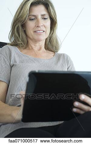 Stock Photo - Woman using digital tablet, low angle view. Fotosearch