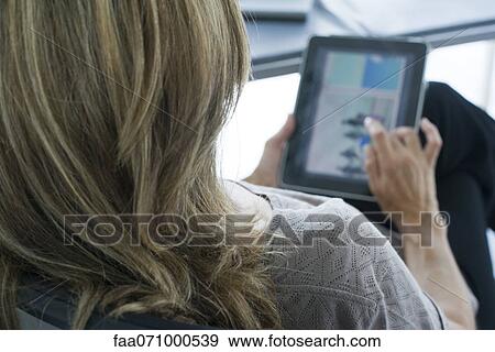 Woman using digital tablet, over the shoulder view View Large Photo Image Stock Photo - Woman using digital tablet, over the shoulder view. Fotosearch