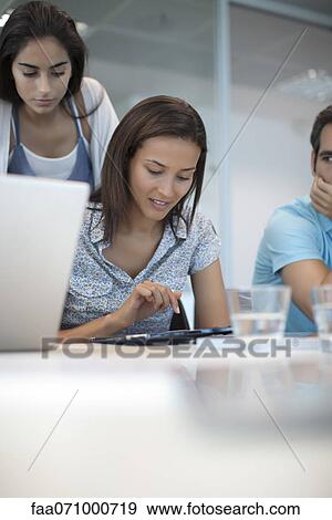Woman using tablet computer while friends watch View Large Photo Image Stock Photo - Woman using tablet computer while friends watch. Fotosearch
