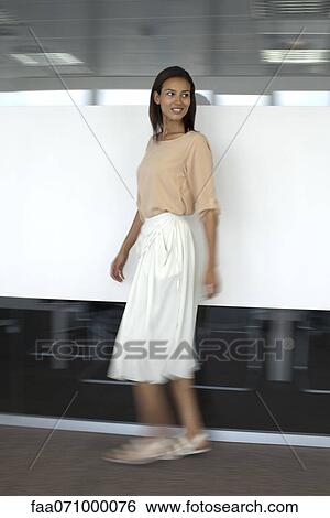 Stock Photograph - Woman walking in office, blurred motion. Fotosearch