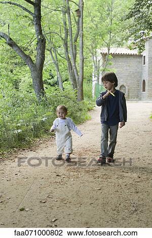Stock Image - Young brothers walking in woods. Fotosearch