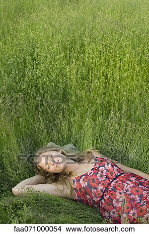 Picture - Young woman napping in tall grass. Fotosearch