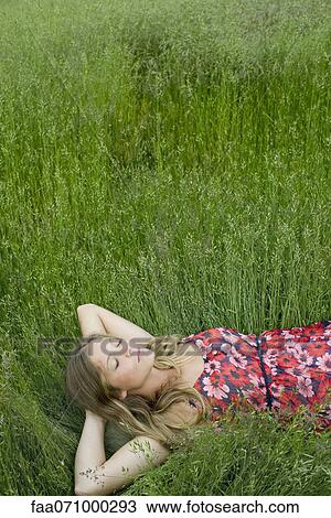 Stock Image - Young woman napping in tall grass. Fotosearch