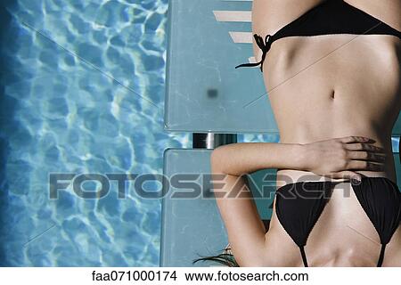 Young woman sunbathing by pool View Large Photo Image Picture - Young woman sunbathing by pool. Fotosearch